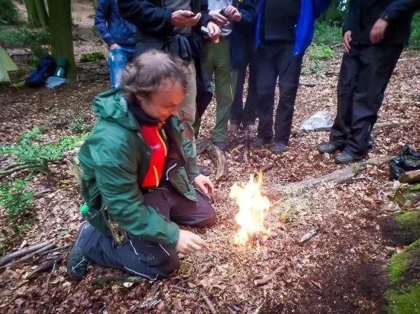 Kleinfeuer brennt auf dem Boden, während jemand Zunder vorbereitet