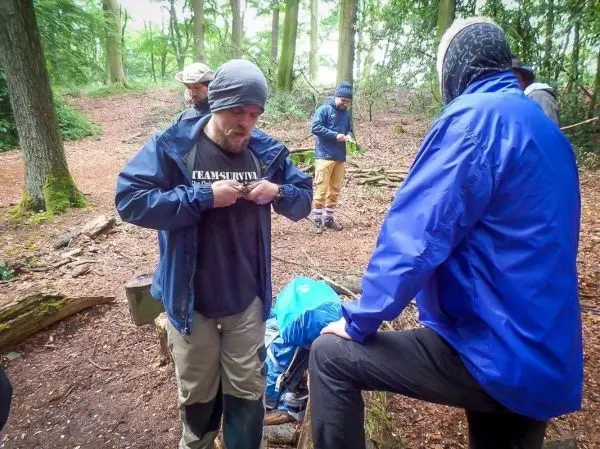 Männer in Outdoor-Bekleidung arbeiten an einer Holzstruktur im Wald