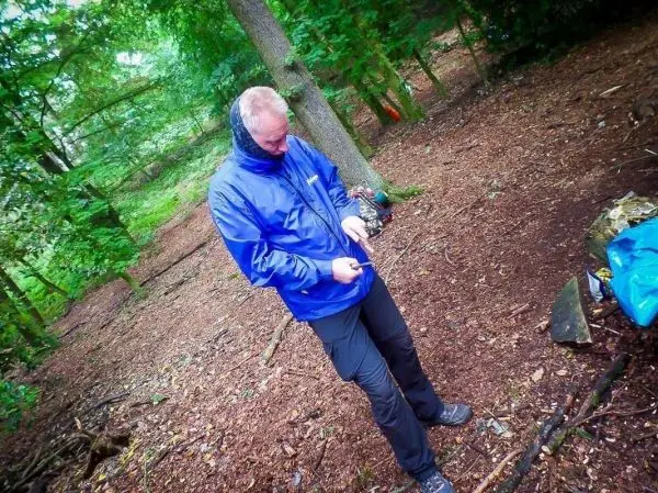 Mann bearbeitet Holzstück mit einem Messer im Wald