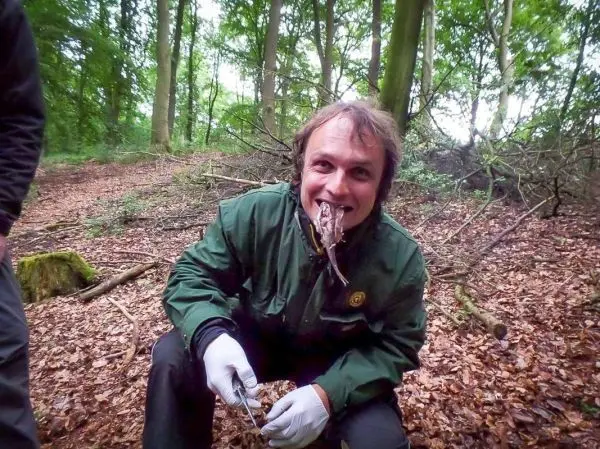 Mann hält einen Stock mit einer Schlange im Mund in einem Wald