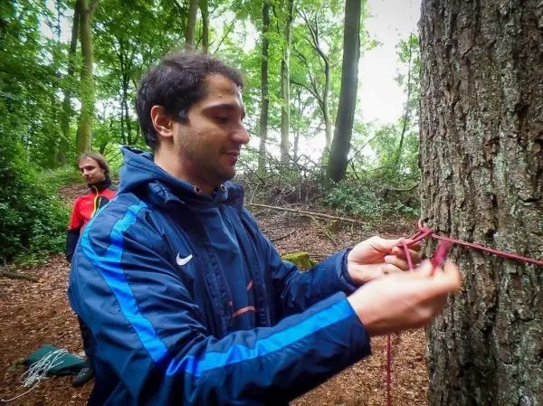 Person bindet ein Seil an einen Baum im Wald