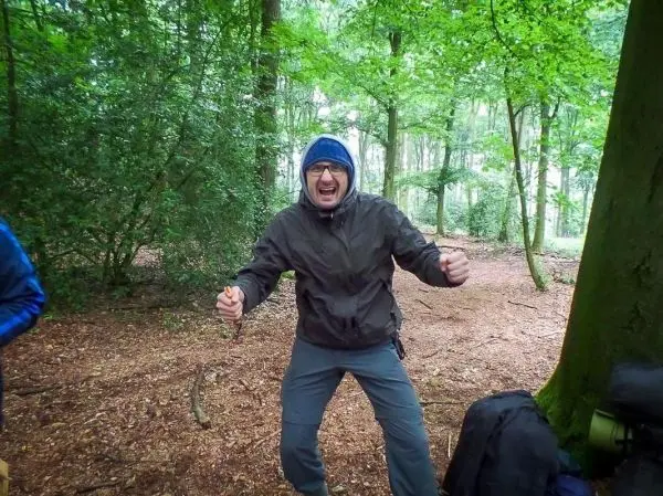 Person steht im wald und hebt die arme nach oben