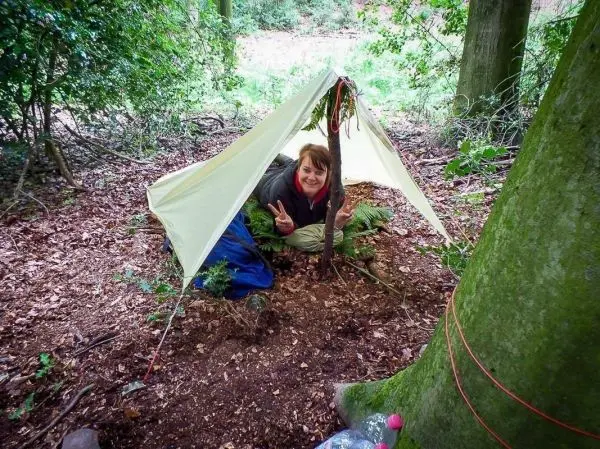 Tarp-Notunterkunft mit einem aufrechten Stock und einer Person darin