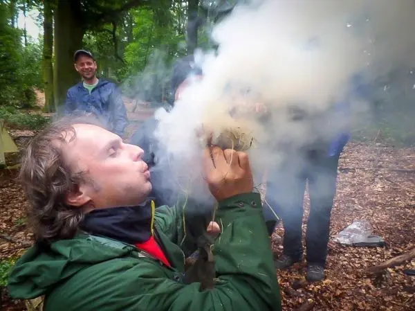 Zunder glimmt während des Blasens in einer Waldumgebung