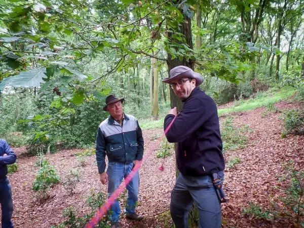Zwei Personen stehen im Wald, eine Person hält ein Seil in der Hand