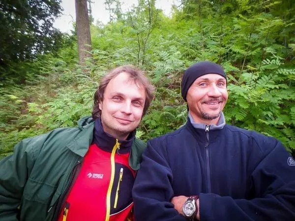 Zwei Personen stehen lächelnd vor grüner Vegetation