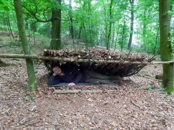 Biwak unter einer selbstgebauten Laubhütte im Wald