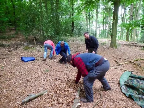 Gruppierung von Personen sammelt Äste und Materialien im Wald für eine Konstruktion