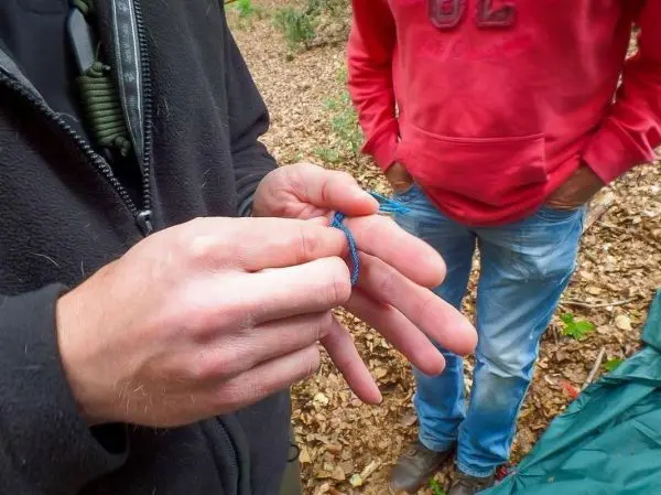 Hände binden eine Schlaufe aus Paracord zur Knotentechnik