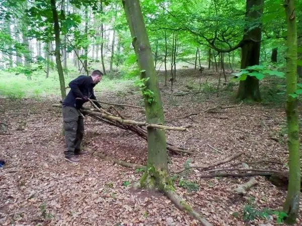 Selbstgebaute Konstruktion aus Ästen wird an Baumstamm befestigt