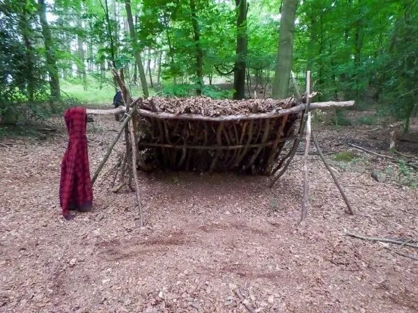 Selbstgebaute Laubhütte aus Ästen und Blättern im Wald