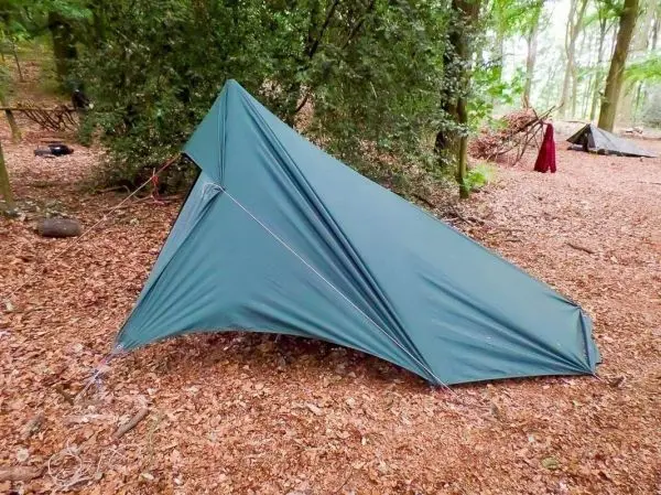 Tarp-Notunterkunft in einem Waldgebiet, mit Abspannschnur gesichert