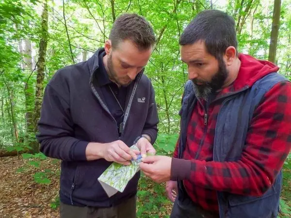 Zwei Personen betrachten eine Karte im Wald beim Überlebenstraining