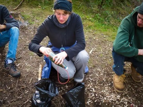 Frau bereitet eine Flasche mit einem Seil und zwei schwarzen Säcken vor