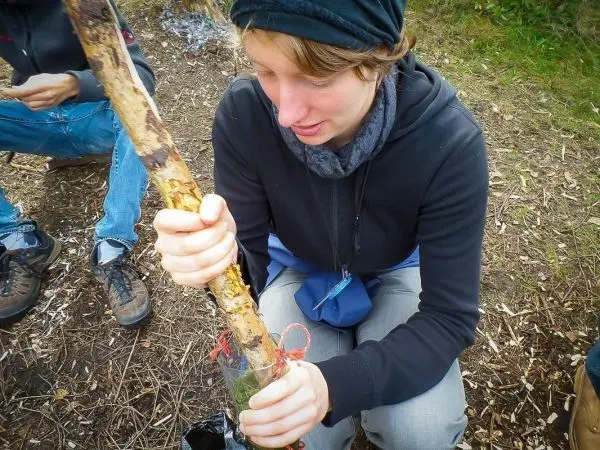 Holzstück wird in ein improvisiertes Gefäß gedrückt