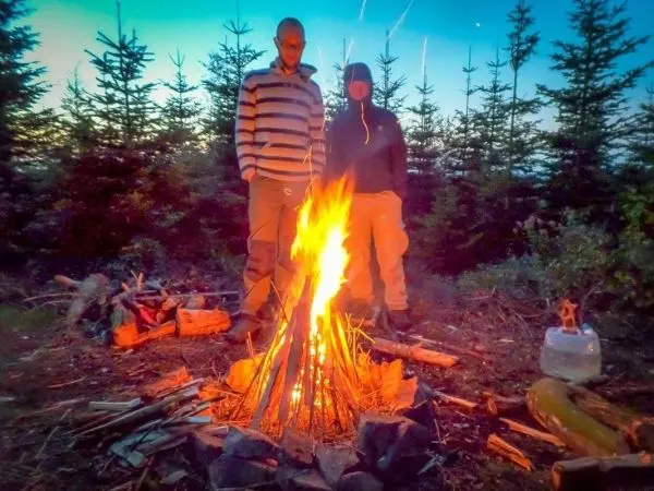 Kleine Flamme brennt in einem Steinkreis, Holz liegt verstreut herum