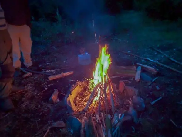 Kleine Flamme brennt zwischen Holzstücken auf dem Boden