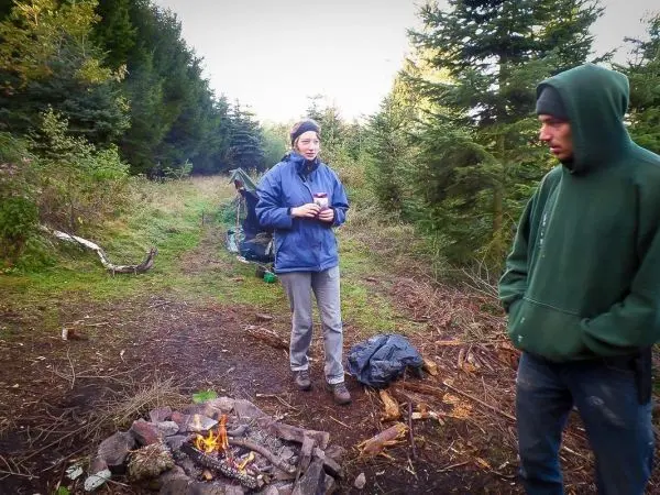 Kleines Bodenfeuer brennt zwischen zwei Personen im Wald