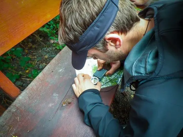 Mann nutzt einen Kompass auf einer Holzoberfläche zur Orientierung