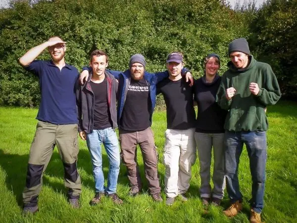 Sechs Personen stehen auf einer Wiese und lächeln in die Kamera