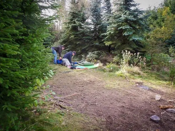 Zwei Personen bereiten eine Schlafunterlage im Wald vor