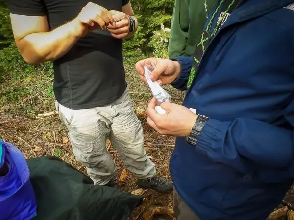 Zwei Personen halten ein kleines Paket in der Hand, während sie im Wald stehen