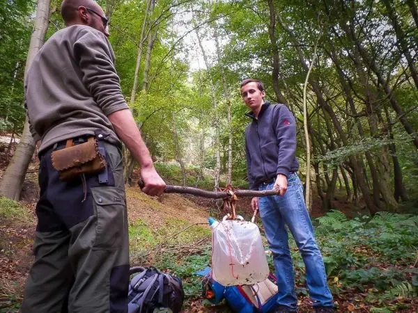 Zwei Personen halten eine improvisierte Trage mit einem Wasserbehälter aus einem Stock