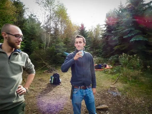 Zwei Personen stehen in einem Waldgebiet, eine hält eine Dose in der Hand