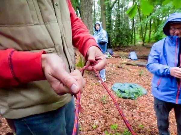 Hände binden ein Seil zu einem Knoten im Wald