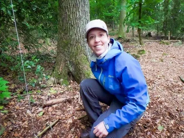 Knieend vor einem Baum, untersucht die Umgebung im Wald