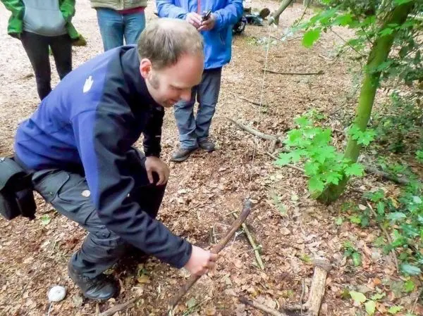 Mann baut eine Schlagfalle (Figure-Four-Falle) im Wald auf