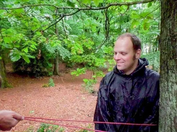 Mann steht an einem Baum, während ein Seil gespannt wird
