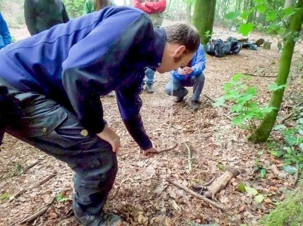 Person zeigt auf den Boden im Wald beim Überlebenstraining