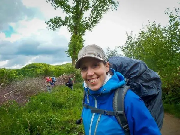 Wandernde Person mit Rucksack auf einem Weg, im Hintergrund weitere Wanderer