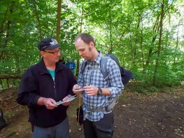 Zwei Personen betrachten eine Karte und einen Kompass im Wald