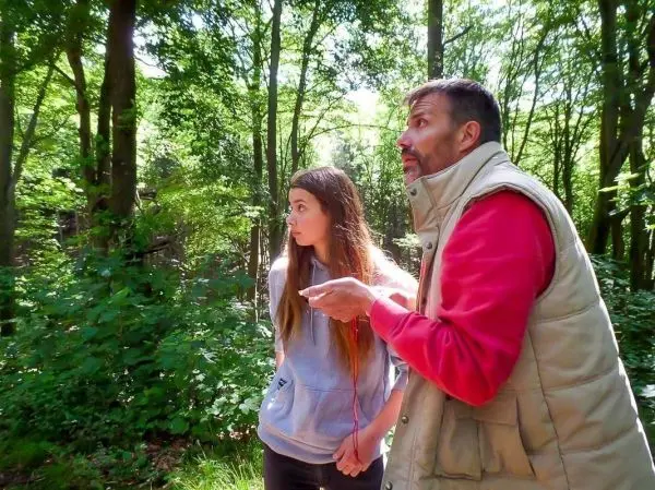 Zwei Personen stehen im Wald und schauen aufmerksam in eine Richtung