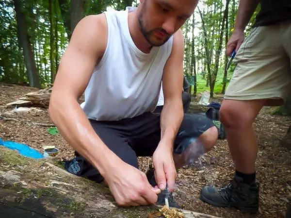 Feuerstahl erzeugt Funken auf Zunder in einem Waldgebiet