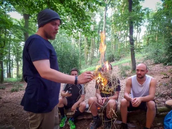 Kleines Bodenfeuer brennt in der Hand eines Mannes, während andere zuschauen