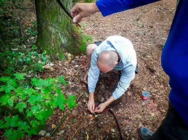 Mann bindet Schnur um einen Stock in einem Waldgebiet