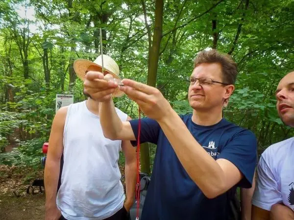 Mann hält eine Schnur mit einem kleinen Gewicht in der Hand, um eine Technik zu demonstrieren