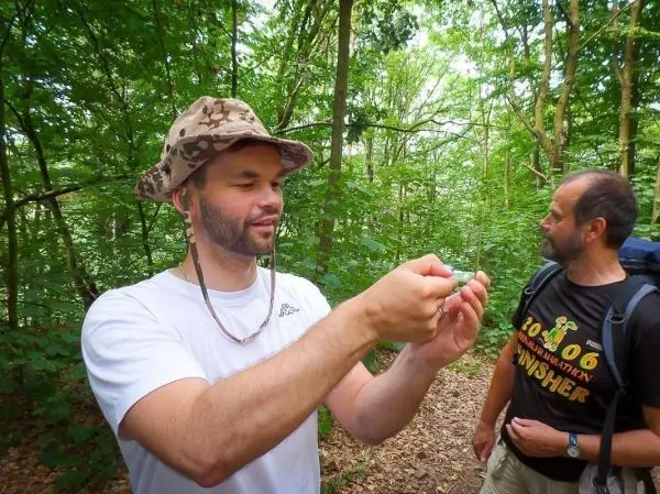 Mann hält einen kleinen Gegenstand in der Hand, während ein anderer Mann zuschaut