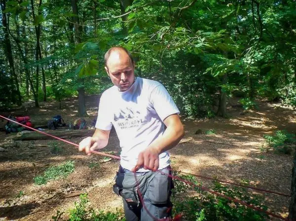 Mann knotet ein Seil in einem Waldgebiet