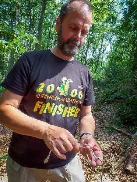 Mann knotet Seil in einem Waldgebiet