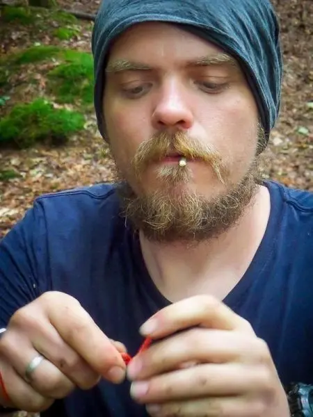 Mann knüpft mit beiden Händen an einem roten Seil