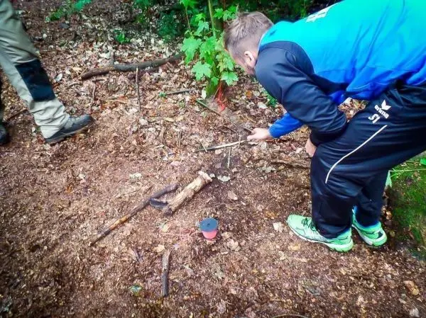 Mann zündet Zunder mit Feuerstahl und Funken in einem Waldgebiet