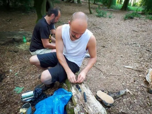 Messer schneidet Holzstück auf einem Baumstamm im Wald