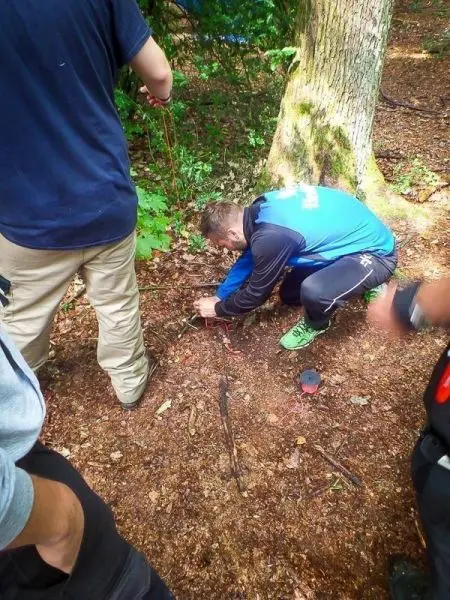 Person baut eine Vorrichtung aus Ästen im Wald auf