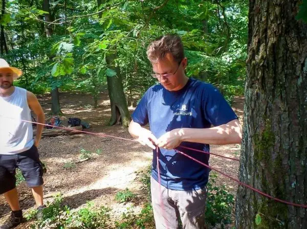 Person bindet ein Seil an einen Baum im Wald