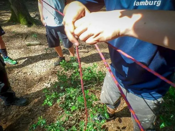 Person knotet Seile im Wald zusammen beim Survival Training