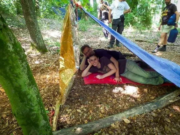 Tarp-Notunterkunft aus blauer Plane und reflektierendem Material zwischen Bäumen